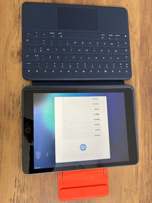 une tablette posée sur un clavier, à côté d'un ordinateur portable