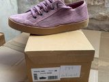 purple sued sneakers with laces on top of a cardboard box
