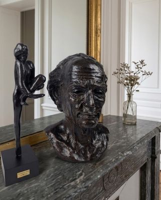 a statue of a man sitting on a table next to a vase of flowers
