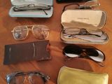 several pairs of glasses and glasses case sitting on a wooden table