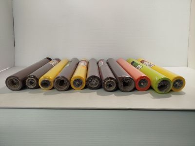 Plusieurs rouleaux de papier coloré sont alignés sur une surface blanche