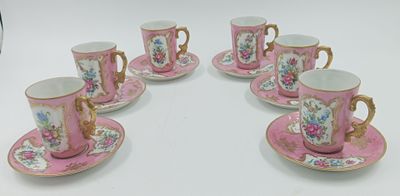 six tasses à café roses et dorées avec leurs soucoupes, posées sur une table blanche
