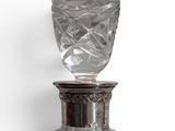 a glass bottle with a silver lid on a white surface