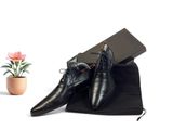 chaussures en cuir noires pour homme, accompagnées d'un sac noir et d'une fleur rose