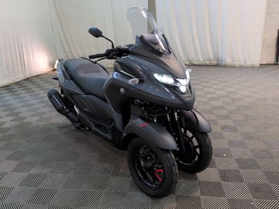 une moto noire garée dans une pièce au sol en damier