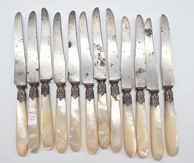 six couteaux d'argenterie avec des manches en nacre, posés sur un plateau blanc