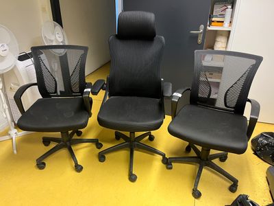 trois chaises de bureau noires posées sur un sol jaune