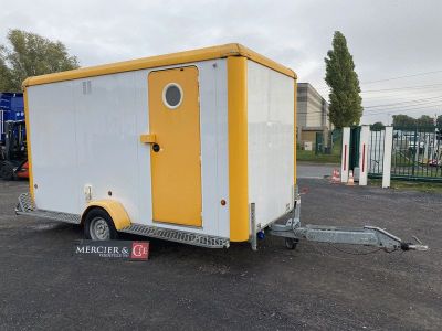 une petite remorque jaune et blanche garée sur un parking