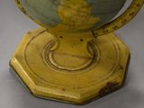 a close up of a yellow and green globe on a wooden stand