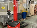 un chariot élévateur dans un entrepôt, avec d'autres équipements en arrière-plan