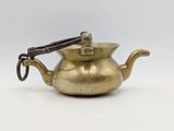 an antique brass teapot with tongs on a white background