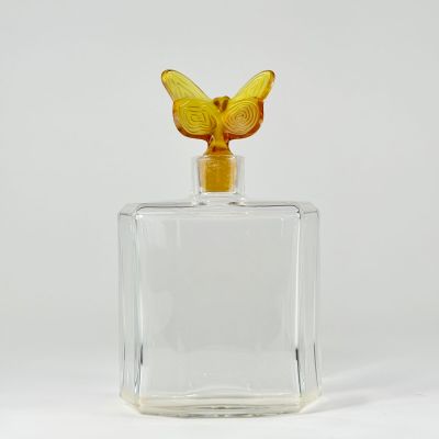 an image of a glass bottle with a yellow butterfly on top
