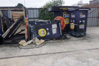 un tas d'ordures devant un immeuble, près d'une clôture