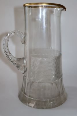 un pichet en verre transparent orné d'un bord doré