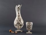 a silver vase and a glass with nuts on a gray background