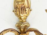 a gold candle holder on the wall next to a white wall