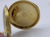 a close up of a gold pocket watch on a white surface