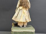 an image of a doll sitting on top of a green suitcase