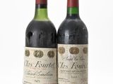 two bottles of red wine sitting next to each other on a white surface