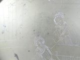 a silver plate with a drawing of two women sitting at a table