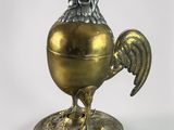 a golden egg shaped like a rooster on a stand