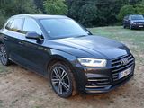 the black audi suv is parked on the dirt in front of some trees