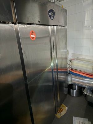 un grand réfrigérateur en acier inoxydable dans une cuisine où il y a beaucoup de vaisselle sur le plan de travail