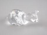 une figurine en verre représentant un chat posée sur une surface blanche
