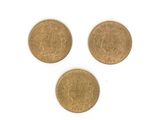 trois pièces d'or sont représentées sur une surface blanche