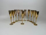 six gold plated wine glasses are lined up on a white surface