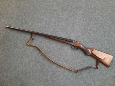 un fusil posé par terre, auquel est attachée une ficelle