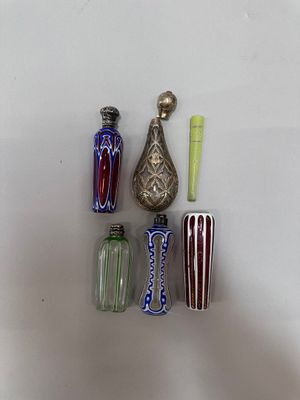 five different colored vases and a silver vase on a white surface