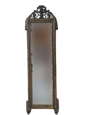 a tall mirror with a decorative design on the top of it