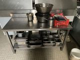 une table en métal sur laquelle sont posés des casseroles et des poêles