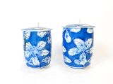 une paire de bougies bleues et blanches ornées de feuilles, sur fond blanc