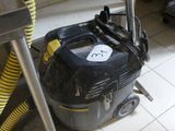 un aspirateur noir et jaune posé par terre dans une cuisine