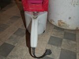 a red and white machine on the floor next to a bucket