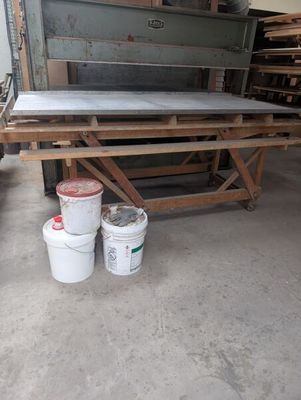 two buckets of paint sitting on a table in a garage