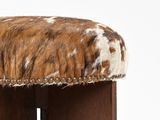 a brown and white cowhide stool with wooden legs