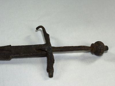 une vieille épée en fer posée sur une surface blanche