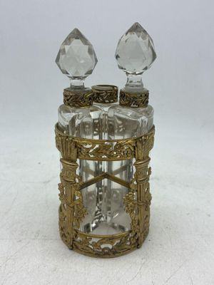 une image représentant un flacon de parfum en verre surmonté de deux gouttes de cristal