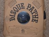 une photo d'un disque vinylique dans une boîte en carton posée sur un sol recouvert de moquette