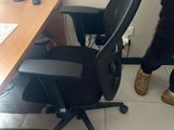 a man standing in front of a desk with a chair