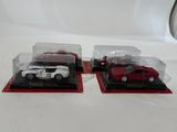 two model cars in a display case on a table