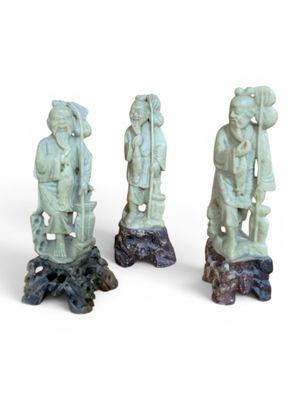 trois statues représentant des personnes d'origine asiatique sont posées sur une souche d'arbre