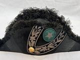 un chapeau noir surmonté d'un bouton vert