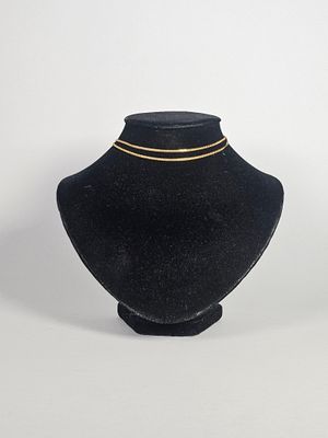 mannequin en velours noir portant un collier à chaîne dorée, sur fond blanc