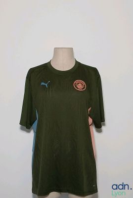 une chemise posée sur un présentoir de mannequin, sur lequel est accrochée une chemise verte et bleue