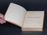 someone is holding a book open on a table with a black background