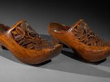 pair of wooden clogs with carved flowers and leaves